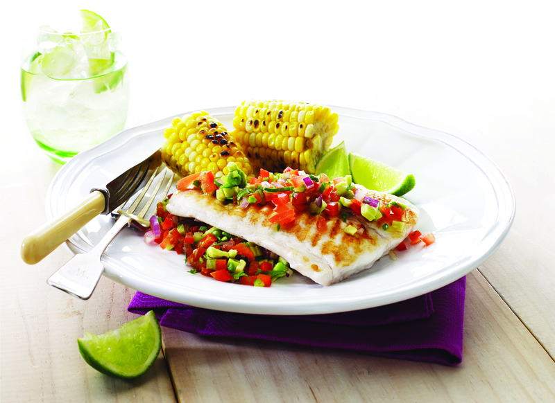 Grilled fish with two corn cobs on a bed of salsa
