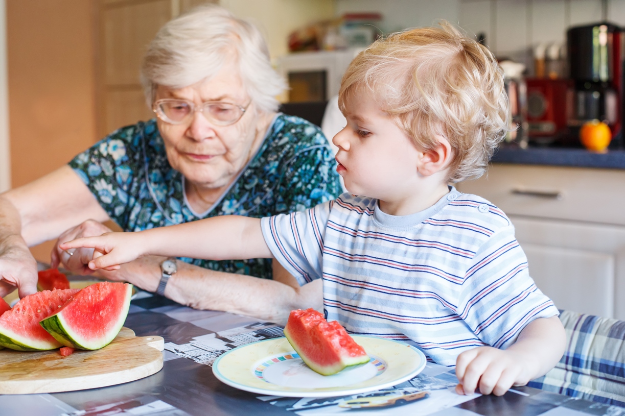Boy eats watermelon with his grandma