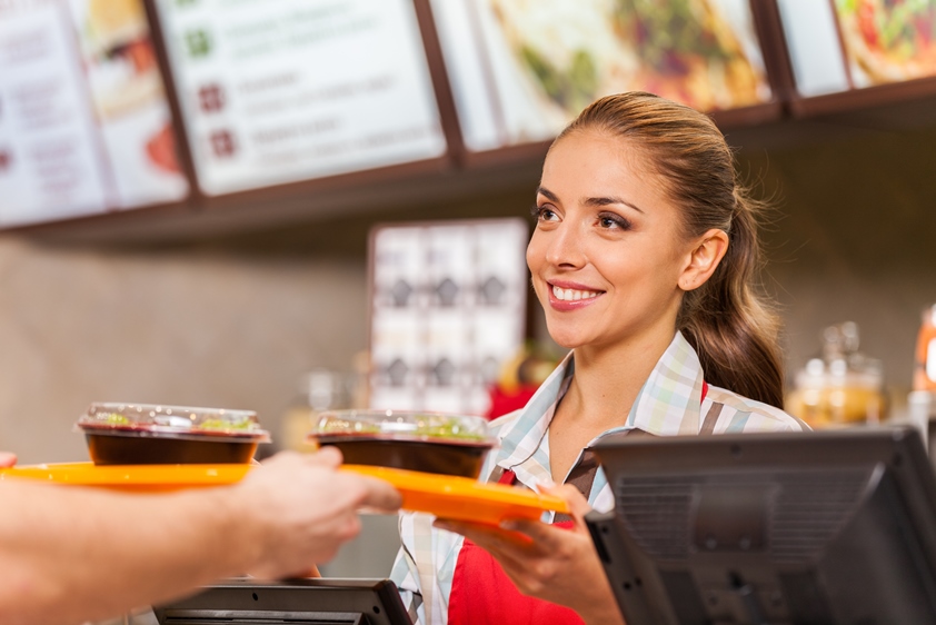 Fast food worker hands over food to a customer