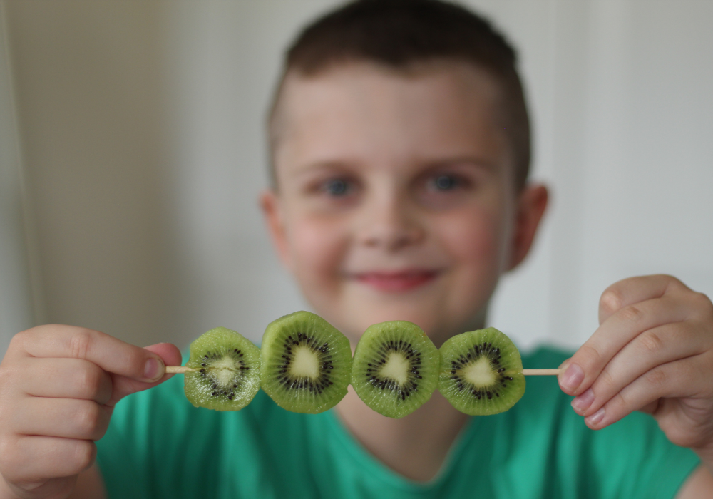 kid holding kiwi slices