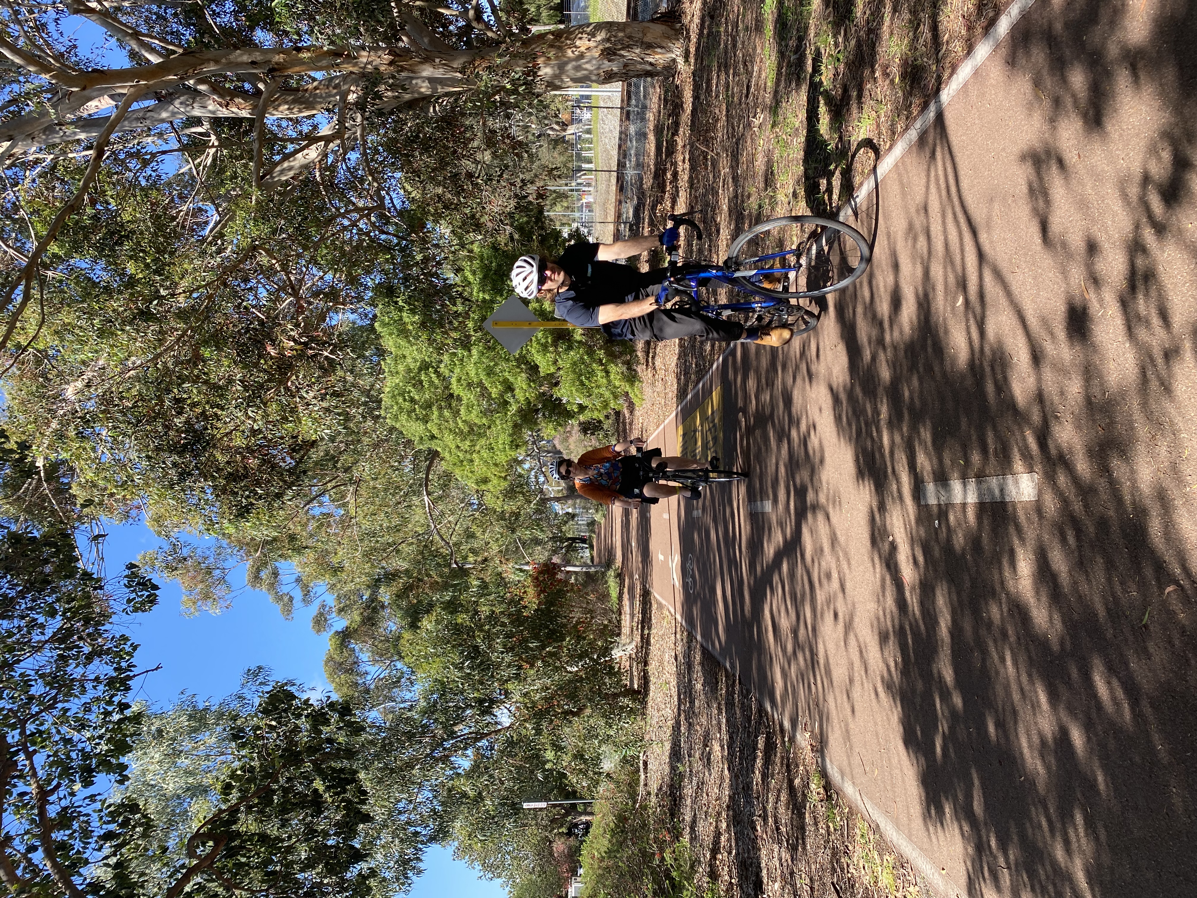 Two people riding a bike on a bike path
