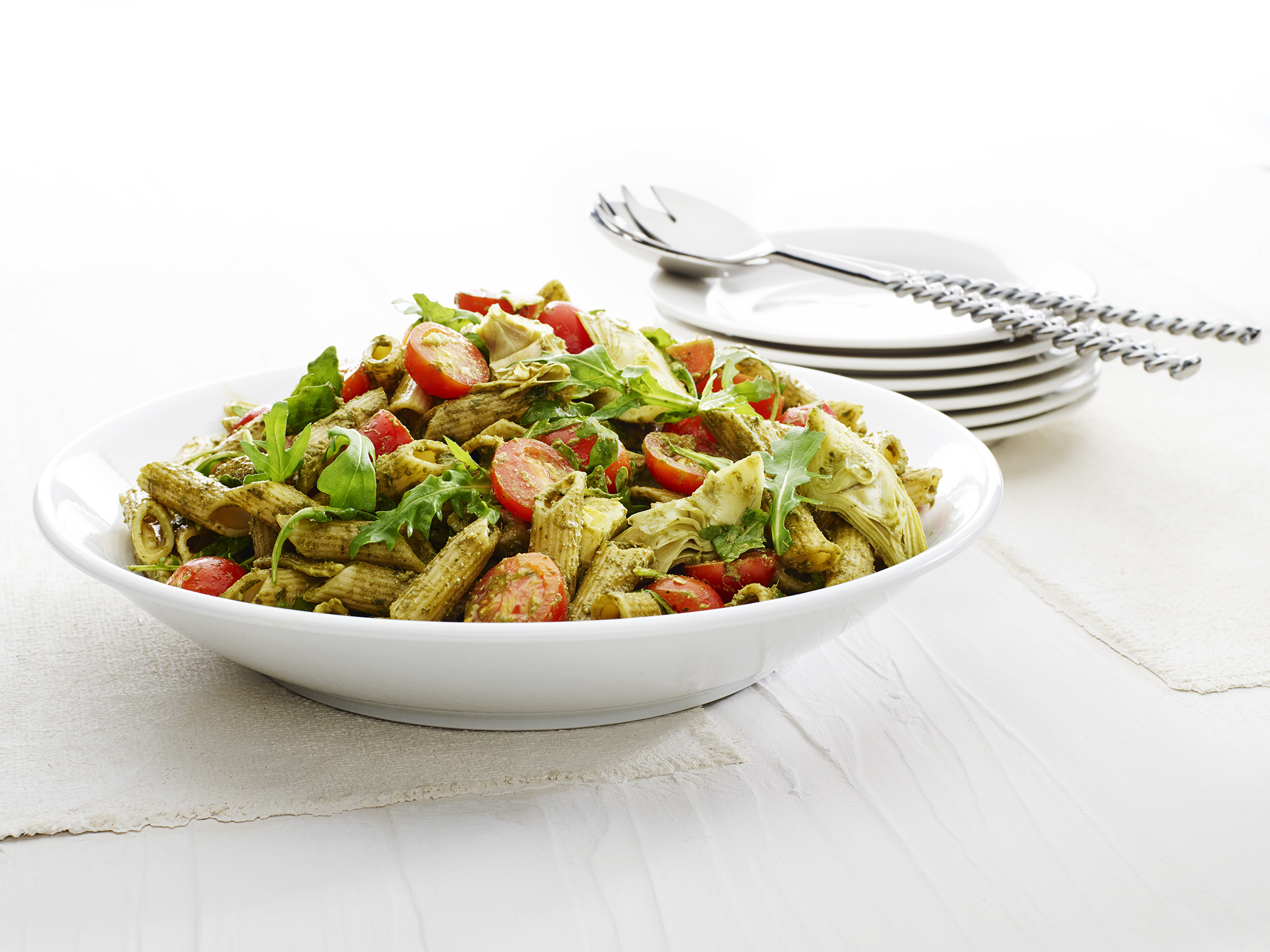 Bowl of pasta with green pesto sauce and cherry tomatoes